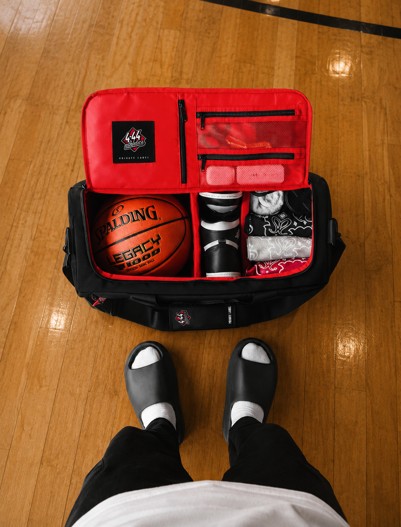Basketball and sports equipment in a red bag on a wooden floor