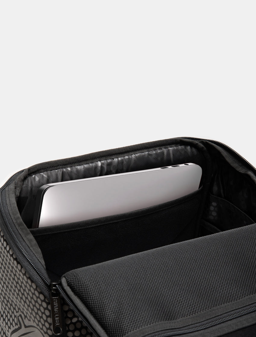 Close-up of an open black backpack or laptop bag showing a padded interior compartment with a silver laptop inside, on a light gray background.