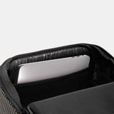 Close-up of an open black backpack or laptop bag showing a padded interior compartment with a silver laptop inside, on a light gray background.