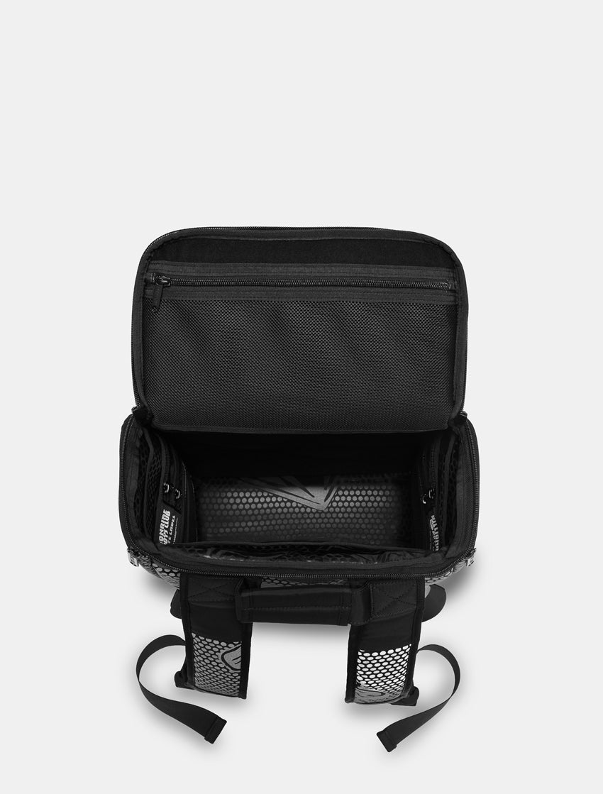 Black backpack shown open from a top-down view, revealing multiple compartments, padded interior, and side mesh pockets, on a light gray background.