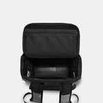 Black backpack shown open from a top-down view, revealing multiple compartments, padded interior, and side mesh pockets, on a light gray background.
