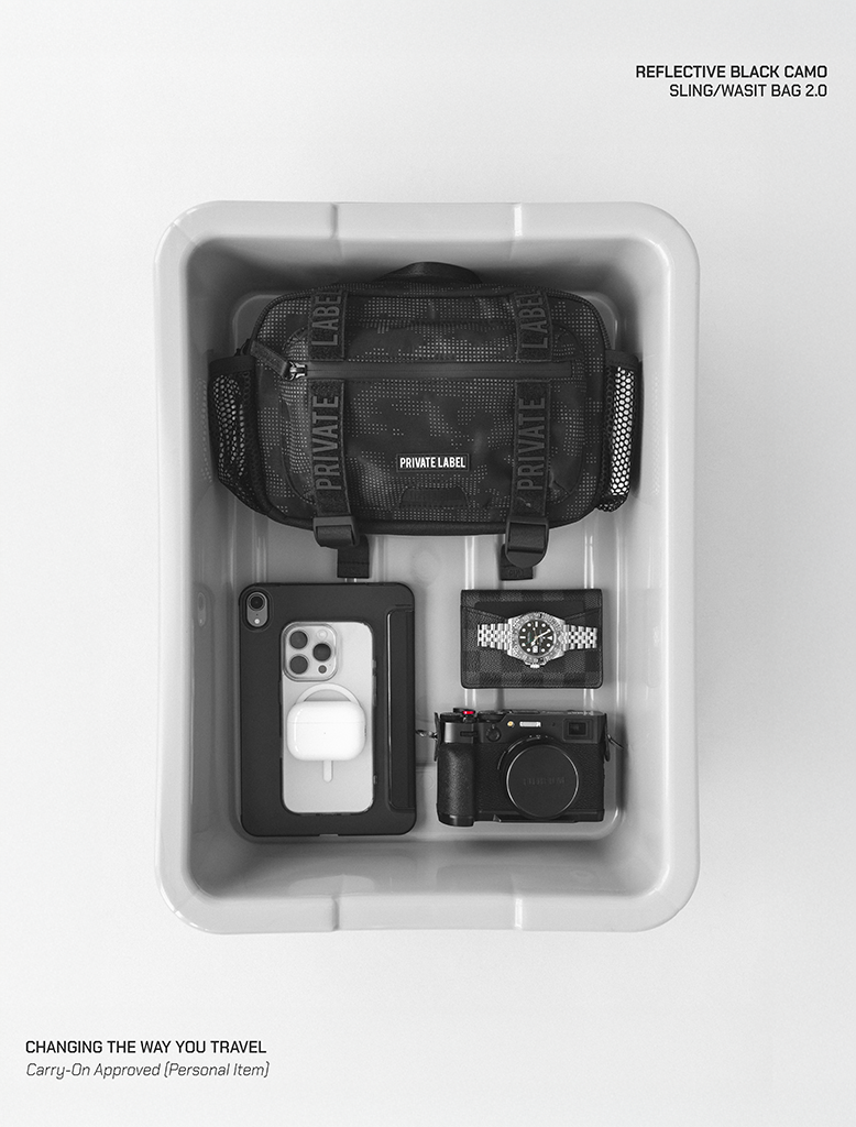 Reflective black camo sling/waist bag with phone, camera, and watch on a white background