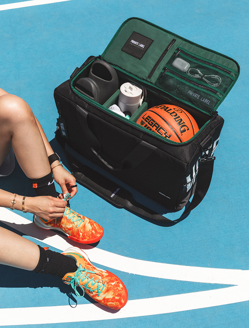 Open black and green carry-on duffle on a basketball court