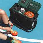 Open black and green carry-on duffle on a basketball court