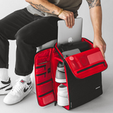 Model puling out laptop from top of backpack and side panel also opened to show multiple access points 