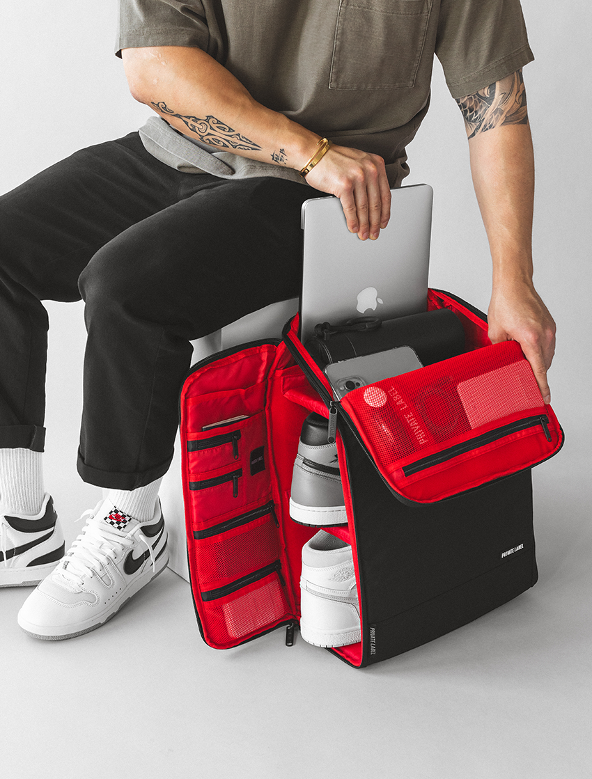 Model puling out laptop from top of backpack and side panel also opened to show multiple access points 