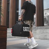 Person walking with a black duffel bag featuring 'Vans' branding on a city street.