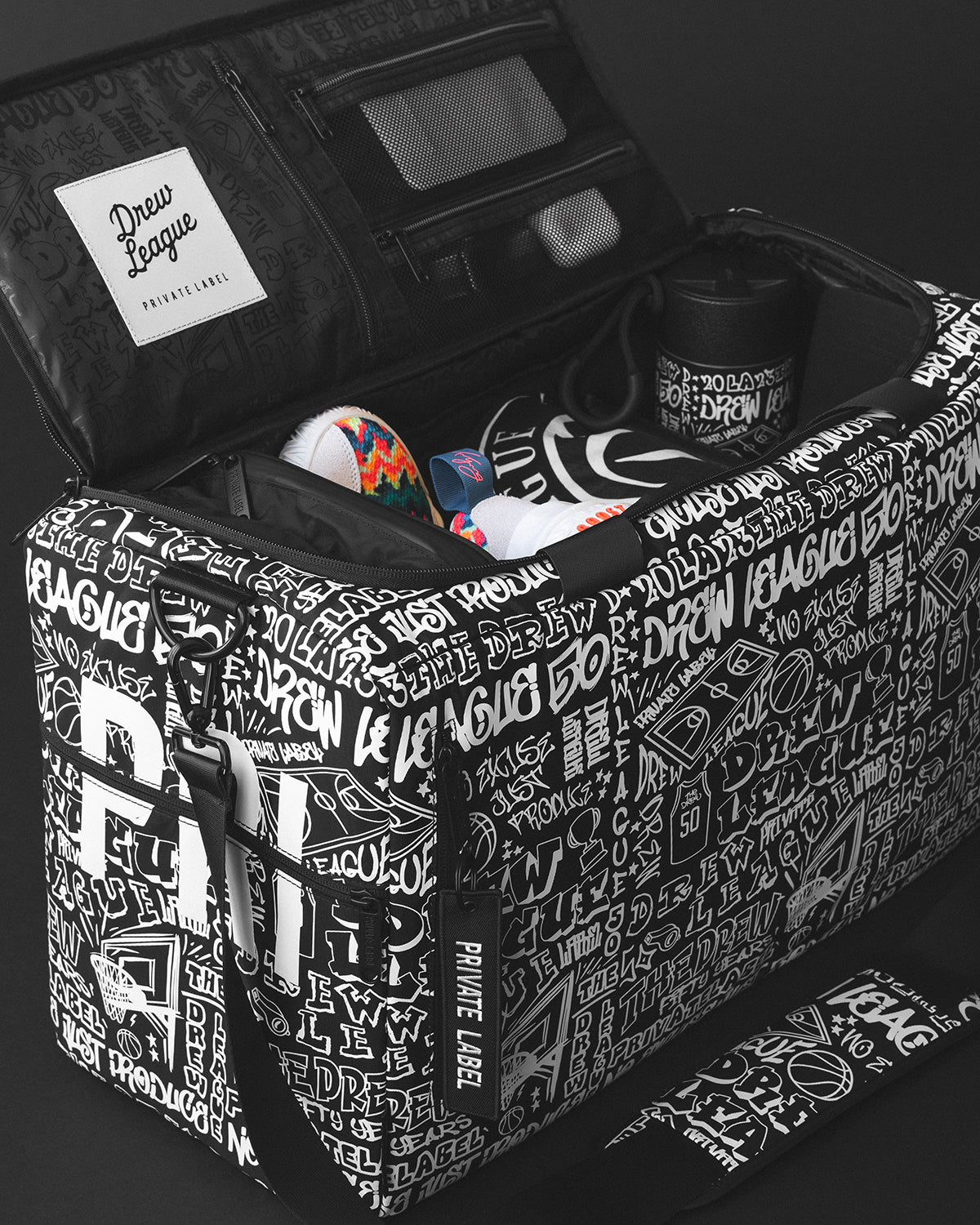 Graffiti patterned duffle collaboration with Drew League and basketball accessories and clothes packed inside.