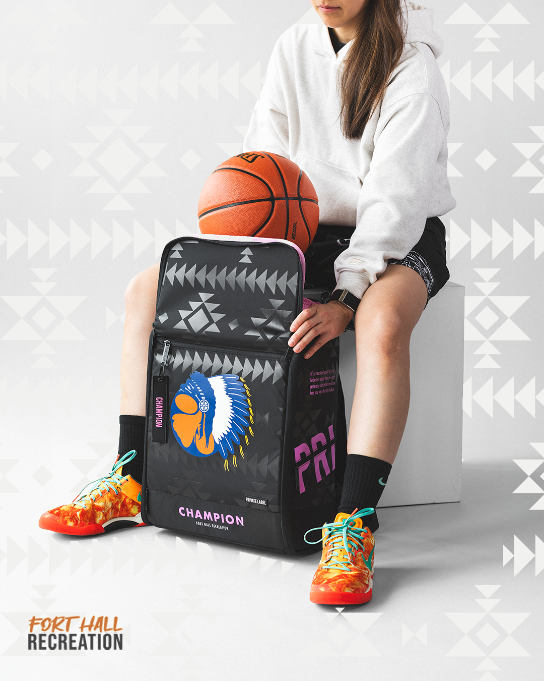 Person sitting with a basketball and a Champion bag on a patterned background