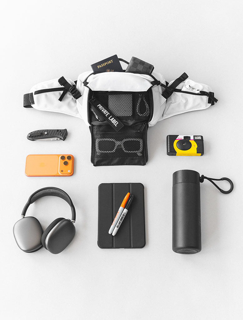 White waist bag surrounded by daily accessories - bottle, headphone, camera and phone
