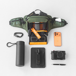 Green Sling Bag with front pocket open & accessories surrounding bag