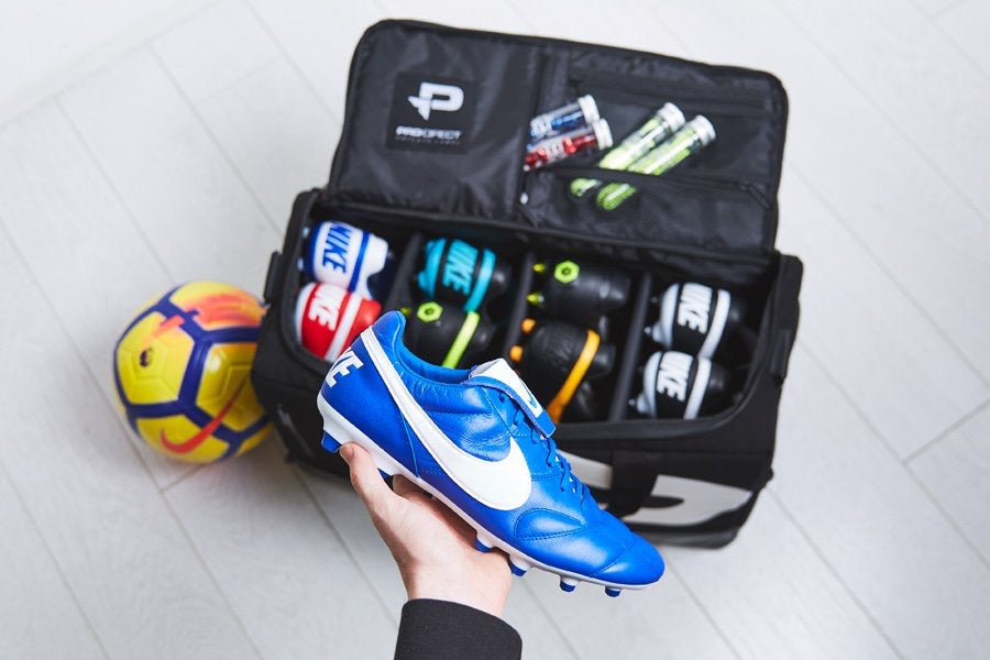 Model holding nike soccer cleats featuring a private label duffle bag packed with more soccer cleats