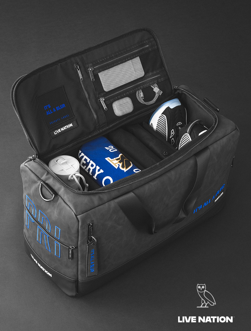 Black duffel bag with electronic devices and a book on a dark background, featuring Live Nation branding.