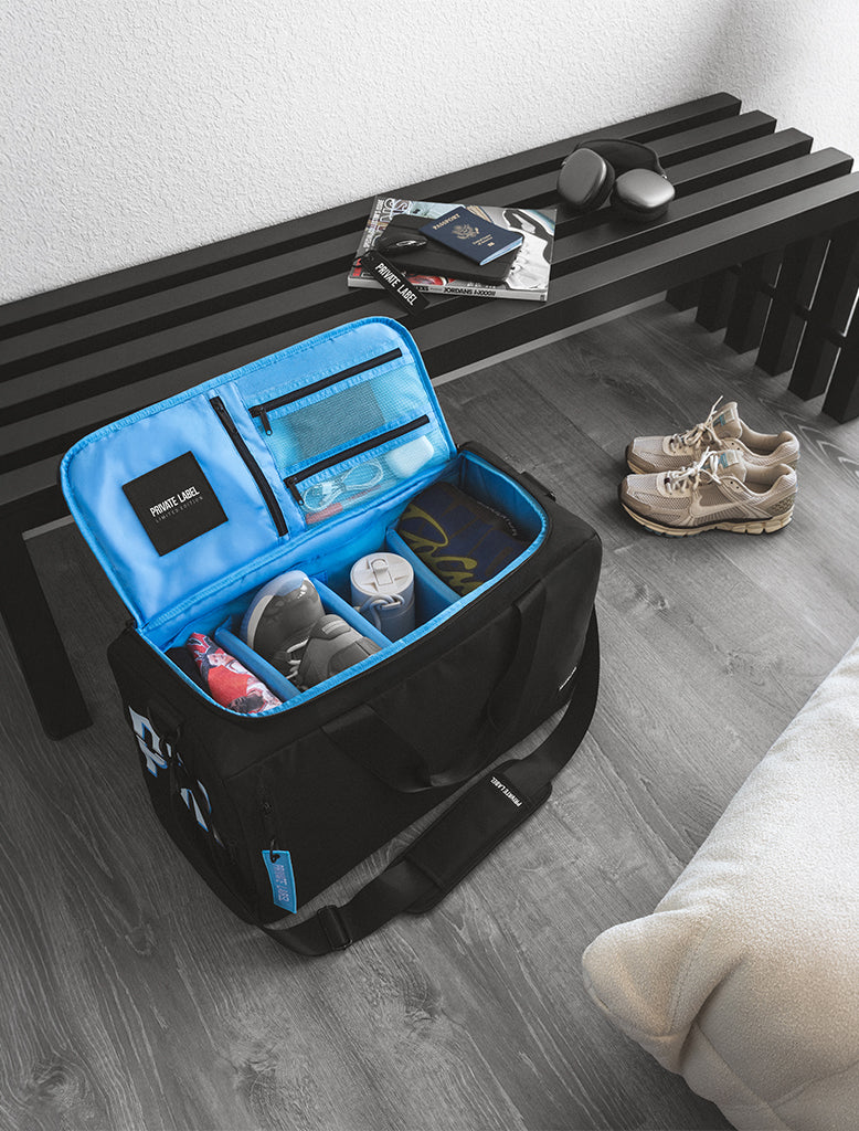 Black bag with light blue interior with shoes and clothes packed inside, sitting in a living room