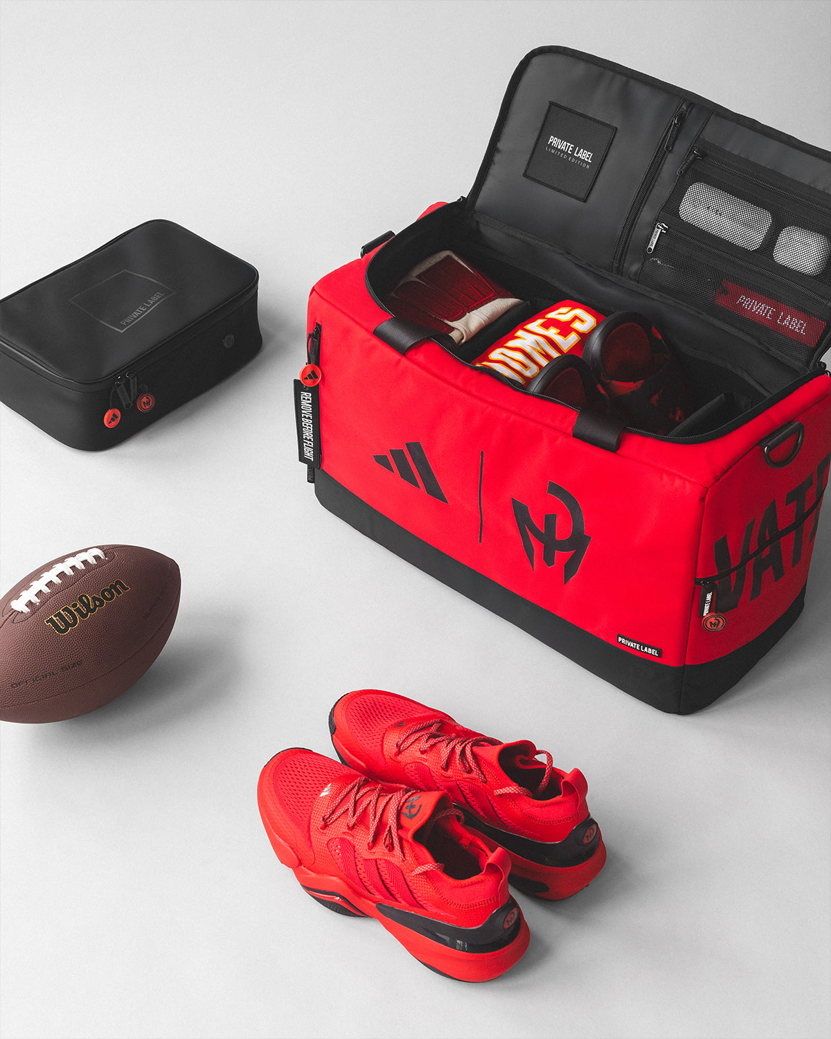 Red Patrick Mahomes x Private Label x Adidas duffle bag with football accessories surrounding the bag