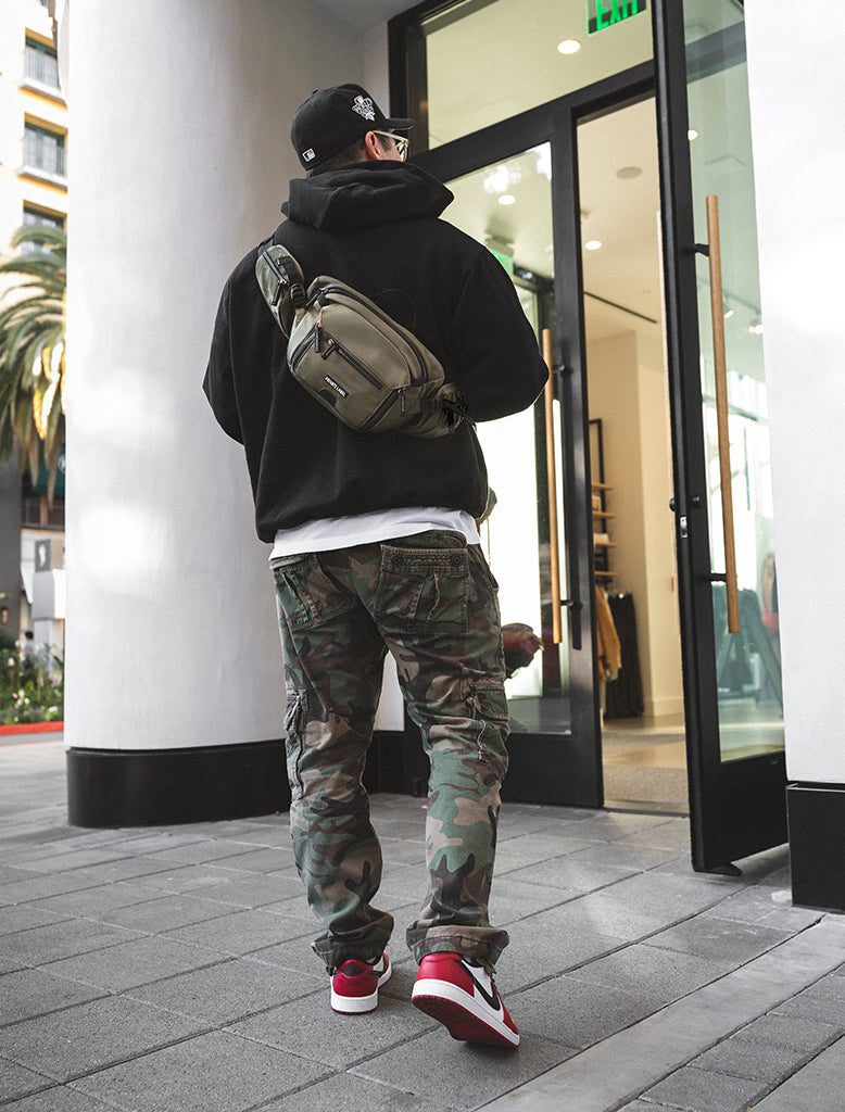 Model wearing Green Sling Bag on back entering retail store