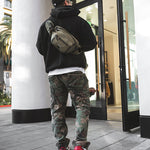 Model wearing Green Sling Bag on back entering retail store