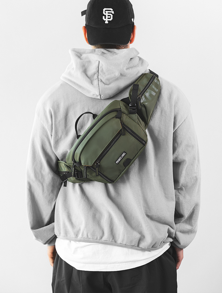 Model wearing cap & hoodie with Green Sling bag on back