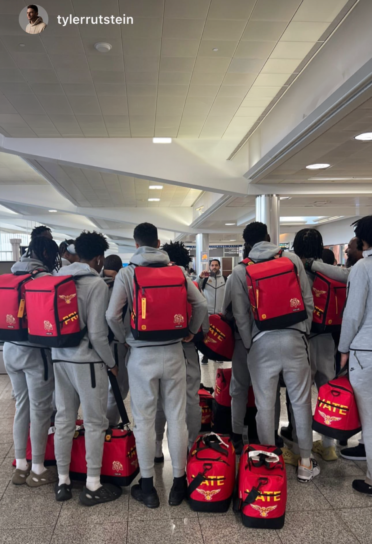 Group of people wearing red bags with visible text in an indoor setting