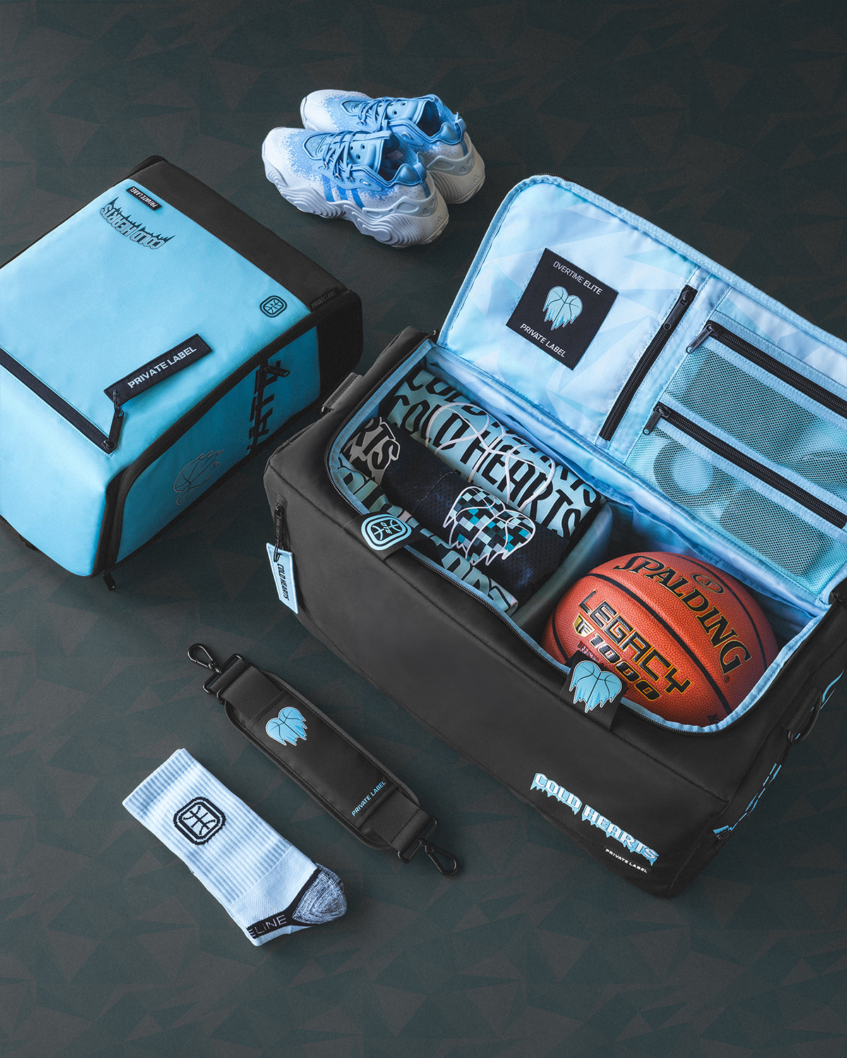 Black duffle with a blue interior packed with basketball accessories and a blue backpack with shoes and socks near by