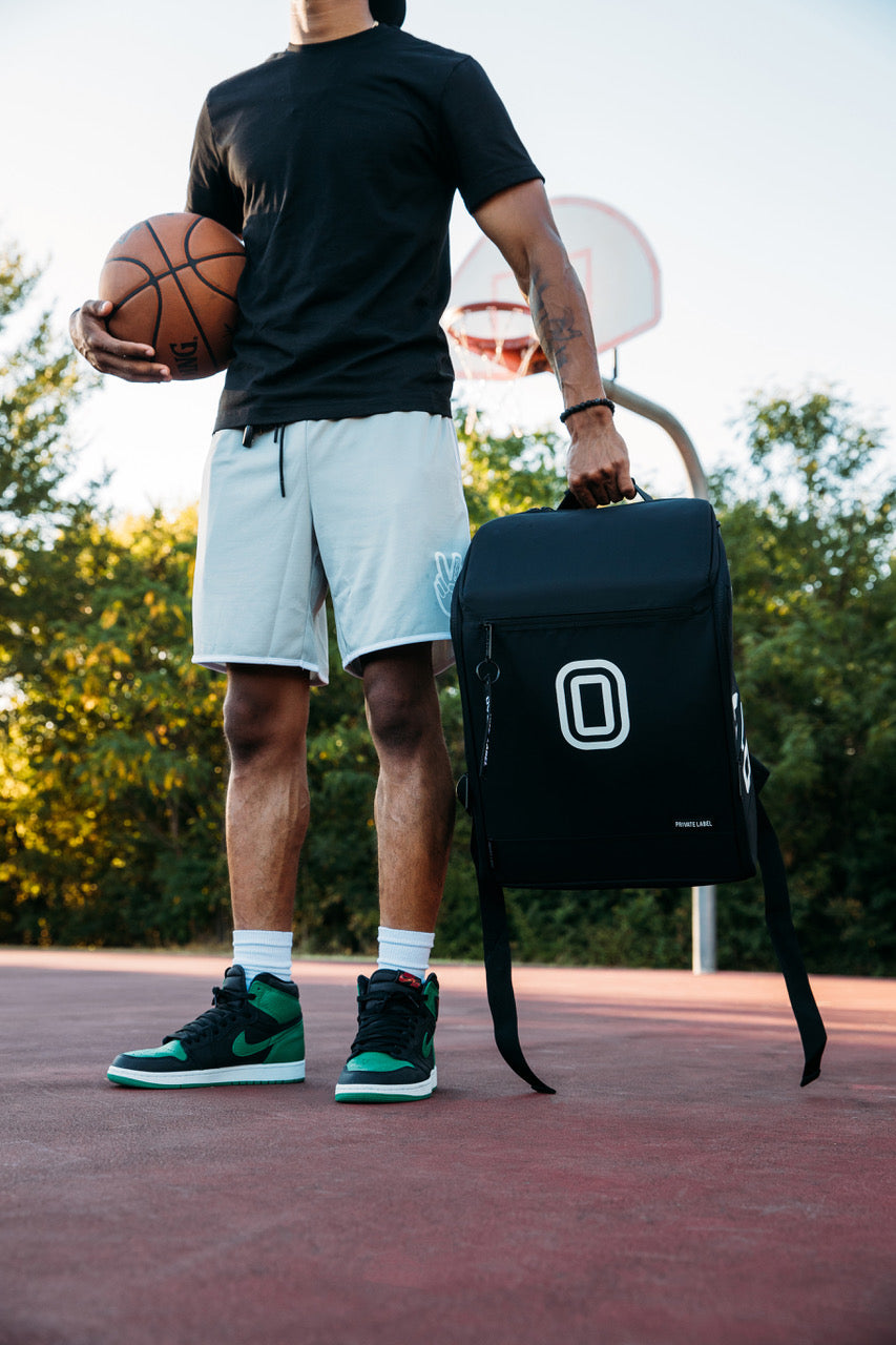 basketball player holding a ball on a court with a black backpack in hand