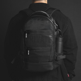 Person wearing a black backpack and cap on a dark background