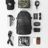 Collection of travel items including a black backpack, camera, passport, and sunglasses on a white background.