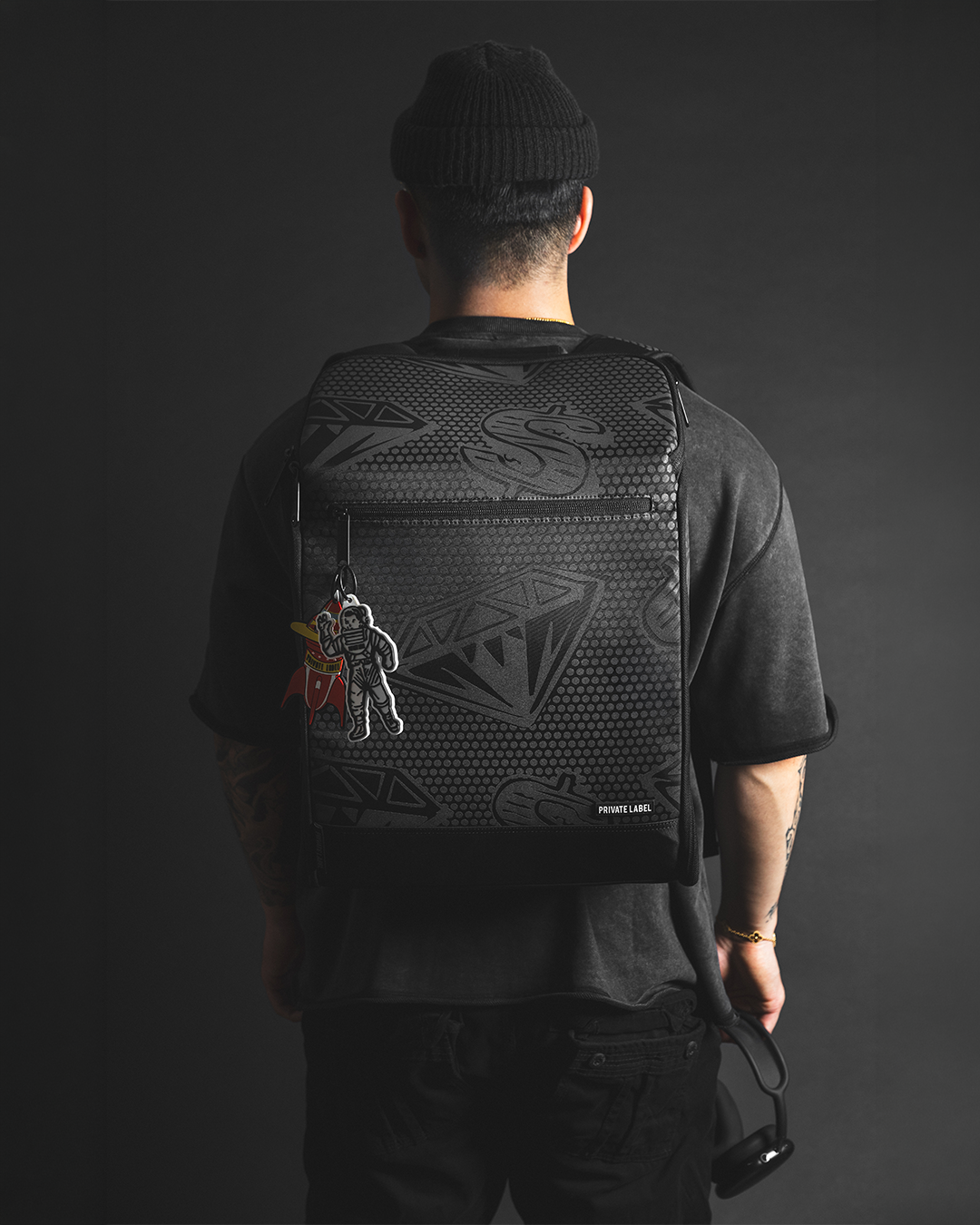 model wearing a black backpack on a dark background with a monochrome outfit