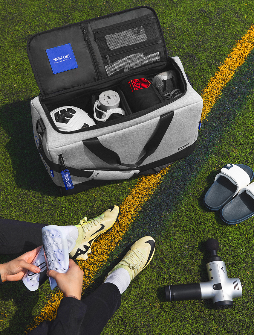 Fleece style duffle with soccer gear packed inside on top of a soccer field