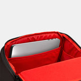 Black backpack with red interior opened showing how a laptop would fit inside the dedicated laptop pocket